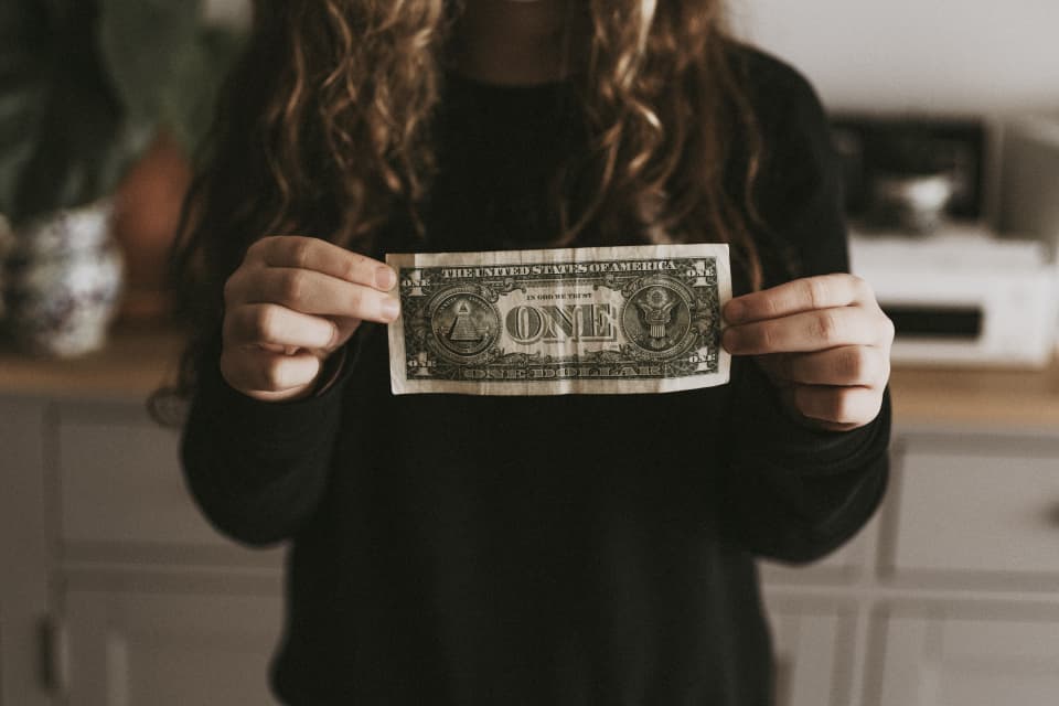Person holding a dollar bill, by Annie Spratt