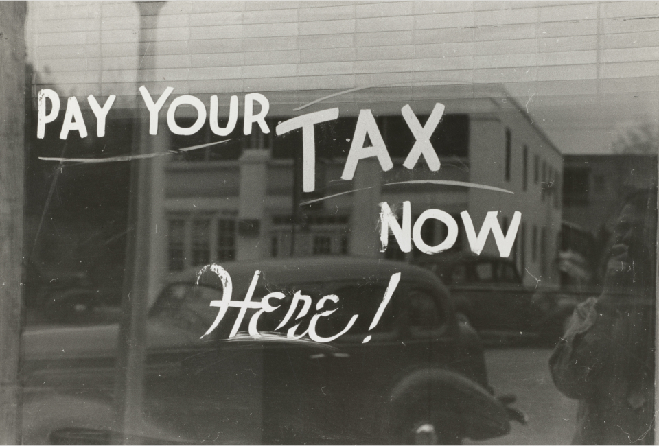 Antique painted window sign that says 'pay your taxes now here!'